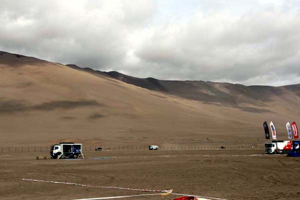 The Hino 500 Series vehicles driving up to the bivouac below the dune hills.