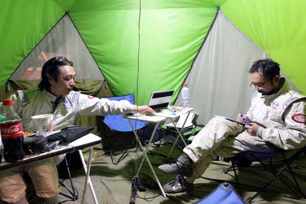 Teruhito Sugawara and Seiichi Suzuki discussing tomorrow's rally in the tent.