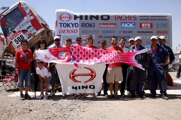 激励に訪れたチリ日野の関係者と寄せ書きされた鯉のぼりを掲げて記念写真に収まる日野チームスガワラ